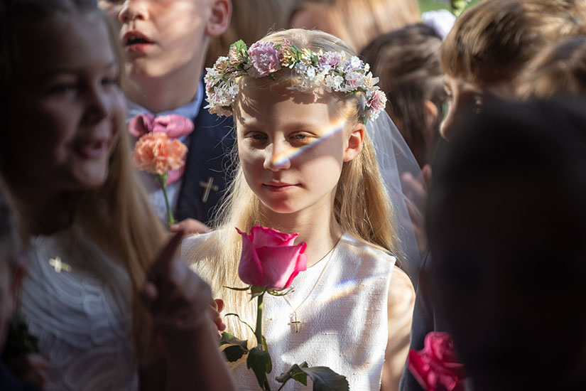 First Communicant Jane Hulsen carried a flower before an opening Mass procession into Mary Queen of Peace Church on May 8 in Webster Groves. The children’s flowers were collected in vases and placed around a statue of Mary, which was crowned during the Mass.